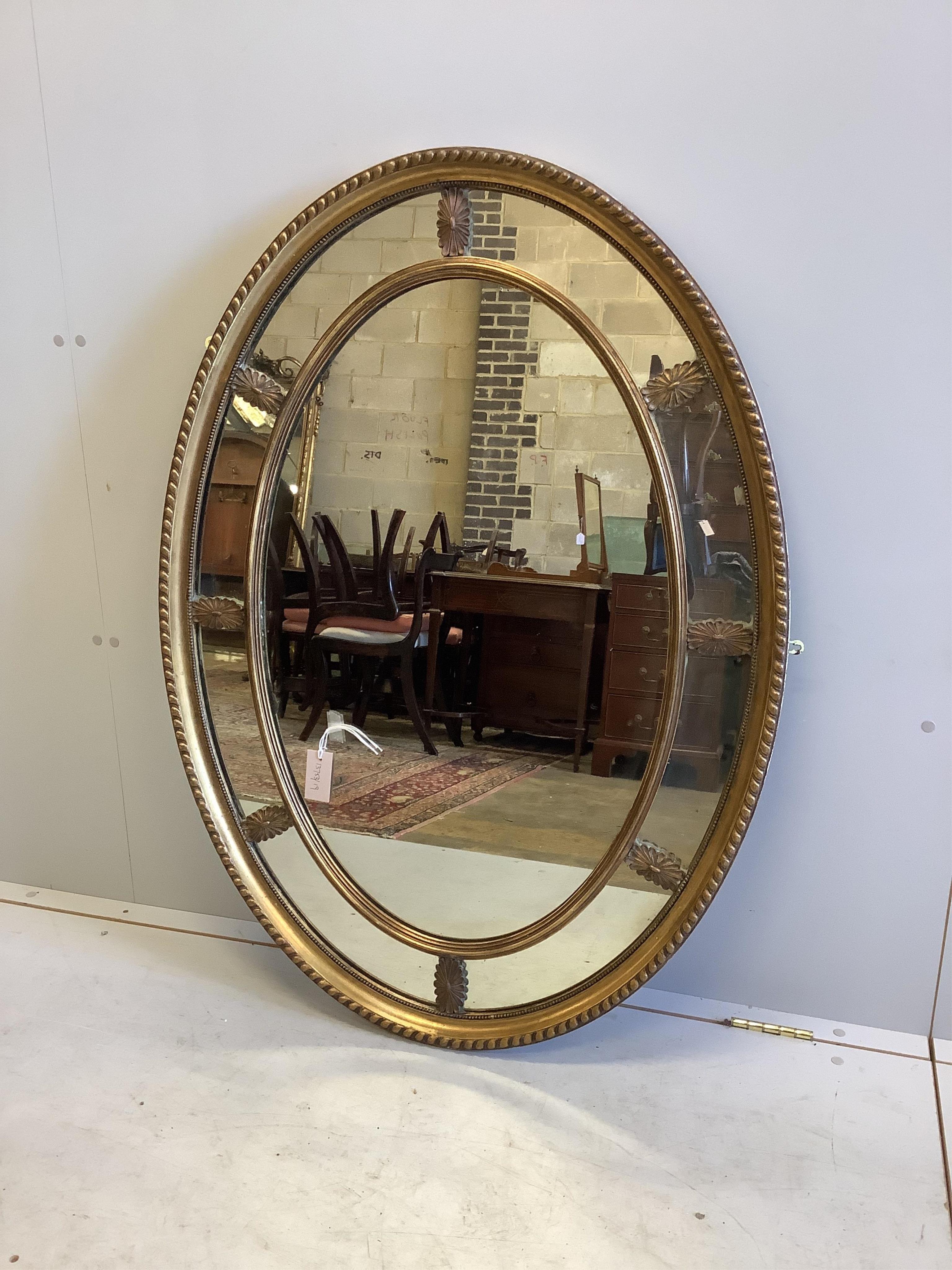 An Adam style oval giltwood wall mirror with marginal plates and acanthus decoration, width 113cm, height 82cm